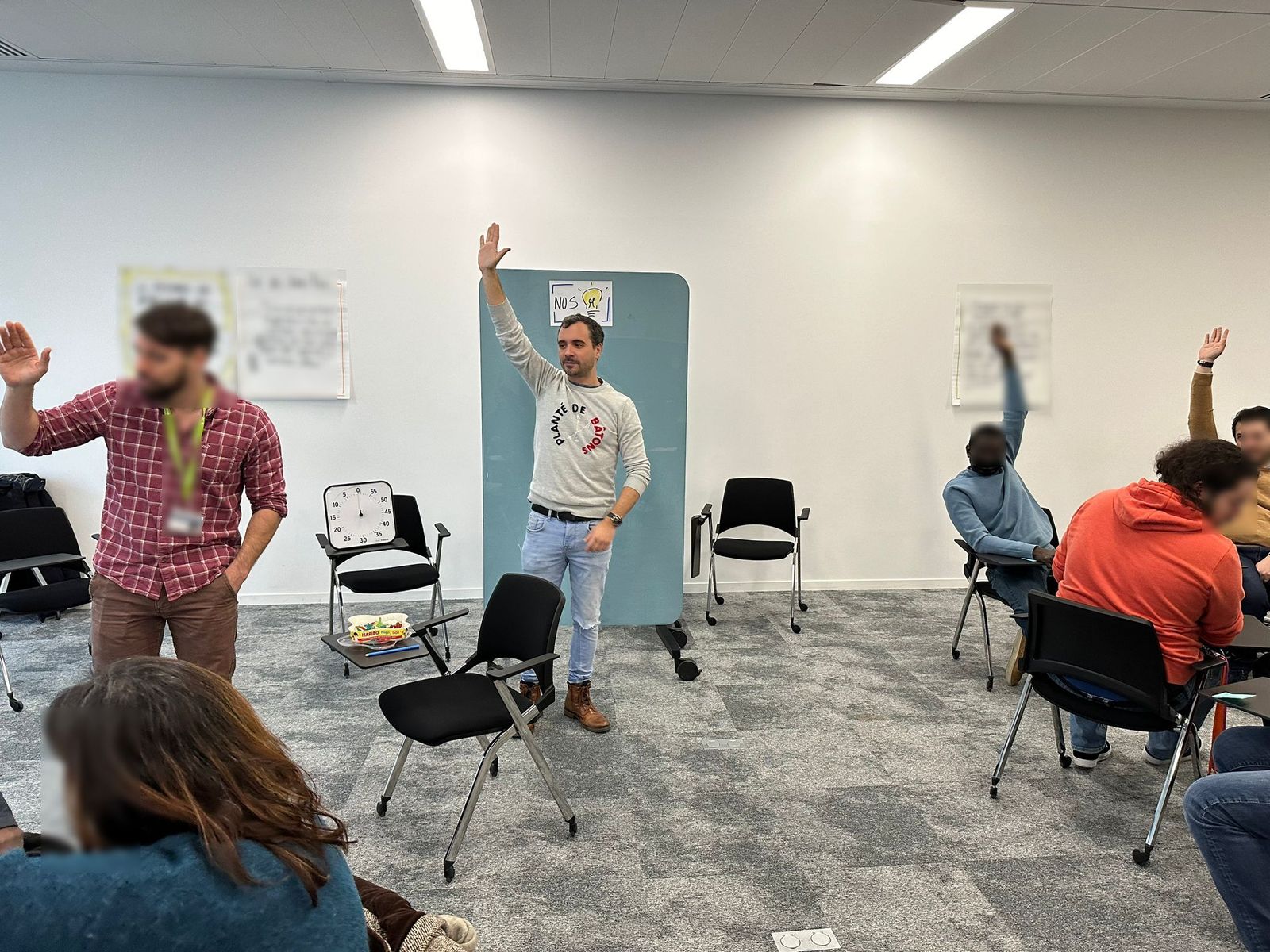 Yoan Lureault en atelier, debout, la main levée, devant un groupe en formation à la facilitation